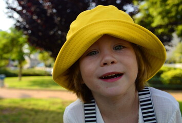 Portrait of a cute boy in a yellow panama hat. A cute child rejoices in the summer. Concept: travel to the resort, holidays with children, kindergarten, holiday, birthday.