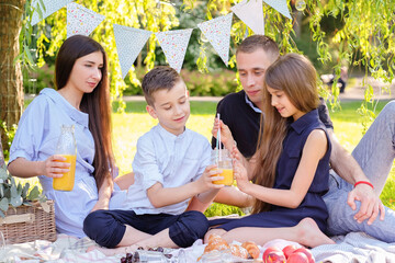 Happy family having a picnic with summer lemonades in the park