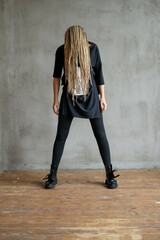 Full-size photo of a young woman with dreadlocks wearing oversize shirt standing and posing against...