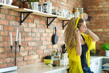 Photo of bright,cool,beautiful woman with dreadlocks enjoying music in yellow headphones while...