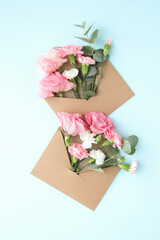 Top view of pink, beautiful flowers in craft envelopes on a white background.