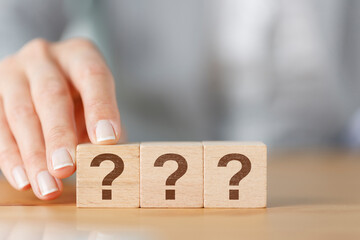 Woman hand holding wooden cube block with question mark.