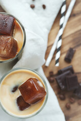 Top view of two glasses of a iced coffee with cream milk and chocolate chips on wooden surface.