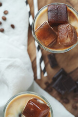 Top view of two glasses of a iced coffee with cream milk and chocolate chips on wooden surface.
