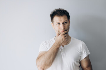 Guy programmer in a white t-shirt holds thinking