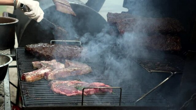 Raw pork chops and ribs meat steaks grilling on stove bbq grill in garden outdoor party food