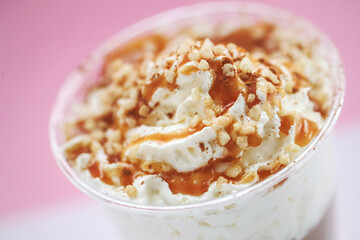 Close view of a tasty caramel milkshake on a pink background.