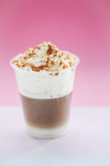 Close view of a tasty caramel milkshake on a pink background.