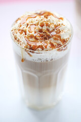 Close view of a tasty caramel milkshake in a glass on a white background.