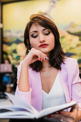 Stylish young ethnic businesswoman reading notes in notepad in cafe