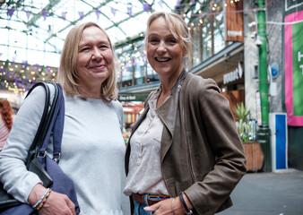 Fototapeta premium Two mature women friends in a street market looking at camera.