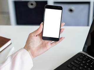 Online conference. Digital mockup. Mobile connection. Unrecognizable woman holding smartphone with blank screen in hand light office room interior.