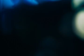 Defocused glow background. Light flare. Optical glare. Blur white blue color spots gleam on dark night black abstract copy space texture.