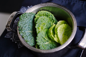 Fresh savoy cabbage leaves waiting to be cooked in pot in the cuisine. Bright green vegetables texture close up. Healthy vegetarian food. 