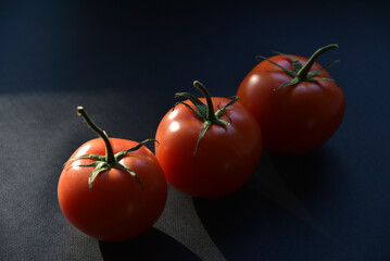 Delicious juicy tomatoes on a black background. Several tomato fruits in close-up.