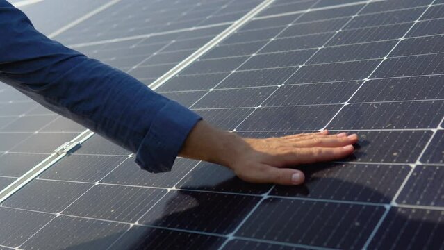 Close up of an young engineer hand is checking an operation of sun and cleanliness of photovoltaic solar panels on a sunset