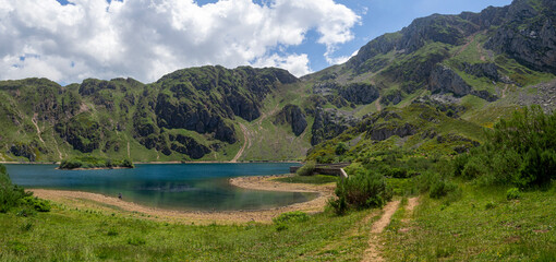 Naklejka na ściany i meble Vistas del lago del Valle con un paisaje de naturaleza verde en las montañas que rodean el lago en Somiedo con formas curvas, verde y azul en Asturias, en verano de 2021