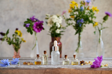 Bottles of essential oil with frankincense, herbs and flowers