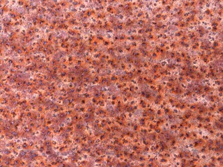 A brown rusty metal surface with dark spots