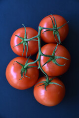 Several delicious red tomatoes in a row on a black background. Juicy red tomatoes close-up.