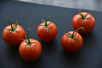 Several delicious red tomatoes in a row on a black background. Juicy red tomatoes close-up.