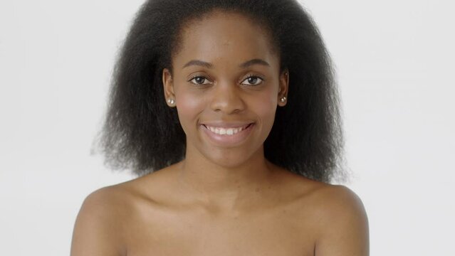Beauty Woman face Portrait. Beautiful Spa model Girl with Perfect Fresh Clean Skin. African American Female with Black Curly Hair looking at camera and smiling. Youth and Skin Care Concept. Isolated