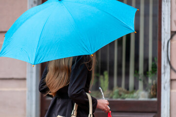 Woman walking on the street in the rain with an umbrella in hand. Real people.