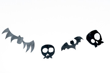 Skulls and flying bats cut out of black paper on a white background, preparation for Halloween.