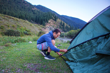 a man sets up a tent in a picturesque place among the mountains