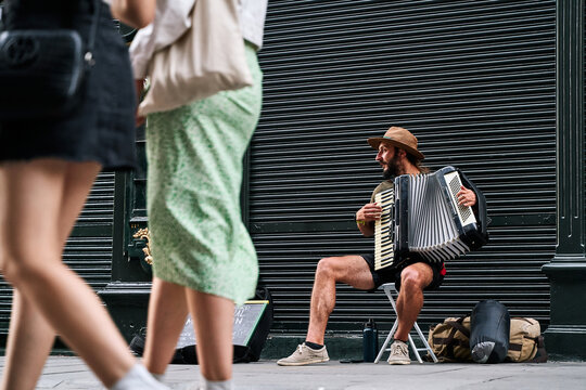 young man with beard playing accordion on a tourist street in portugal lisbon, asking for donations for playing music
