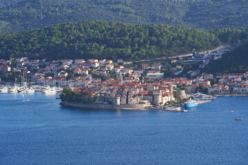 Fototapeta na wymiar Panoramatic landscape picture of the old medieval scenic town Korcula in Croatia in south Dalmatia region in Europe. Picture is taken from mountain at Peljesac peninsula during hot summer evening.