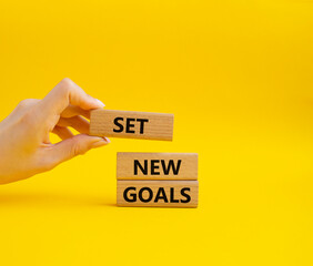 Set New Goals symbol. Wooden blocks with words Set New Goals. Beautiful yellow background. Businessman hand. Business and Set New Goals concept. Copy space.