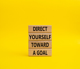 Direct yourself toward a goal symbol. Wooden blocks with words Direct yourself toward a goal. Beautiful yellow background. Business and Direct yourself toward a goal concept. Copy space.