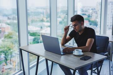 Happy man in optical glasses for vision correction looking for funny information in social networks using wireless connection on netbook, technology concept
