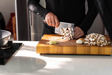 Close up of Chef cook hands chopping champignons. Professional chef cook cutting mushrooms for...