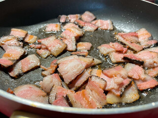 Fried fat bacon close-up in a frying pan, butter with bubbles close-up.