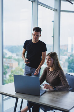 Two Colleagues Are Discussing Work On A Laptop. Friendly Relations In The Office Between Colleagues. Workflow In The Office