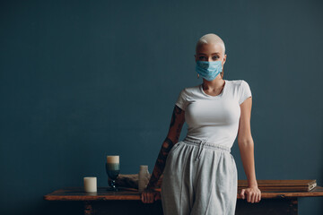 Millenial young woman in medical protective face mask with short blonde hair portrait standing indoor apartment