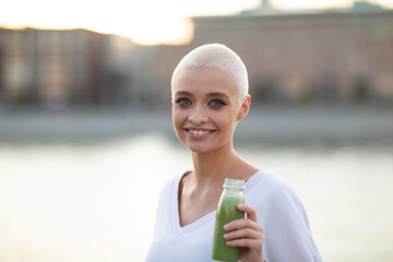 Portrait of young smiling millenial european short haired woman with green smoothie. Beautiful...