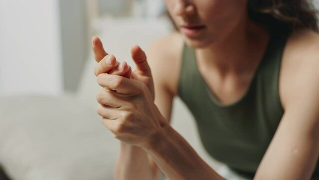Woman in emotional distress rubbing her shaking hands sad and tired is highly agitated being at home close-up. Mental health problems and receiving bad news