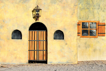 Bright yellow painted and textured adobe or stucco wall like Southwestern style with wood shuttered...