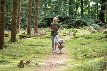 Naklejka na ściany i meble Woman and dog running in forest