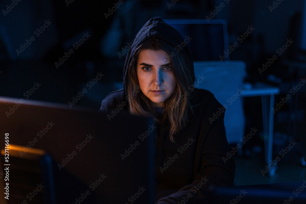 Poster cybercrime, hacking and technology concept - female hacker in dark room writing code or using comput