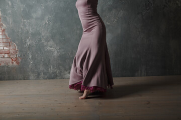 Young adult spanish woman dancing flamenco on gray vintage studio background legs close up - obrazy, fototapety, plakaty