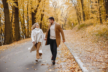 Fototapeta premium Romantic couple walking in autumn forest and holding hands