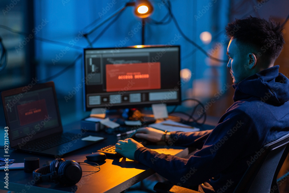 Poster cybercrime, hacking and technology concept - male hacker in dark room writing code or using computer
