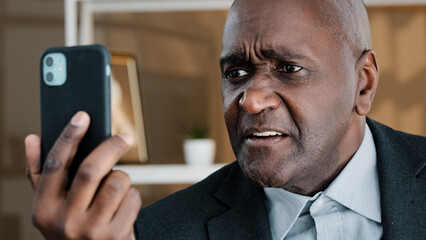 Angry mature elderly African business man having emotionally unpleasant conversation video call...