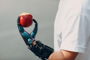 Young disabled man hold apple with artificial prosthetic hand in casual clothes