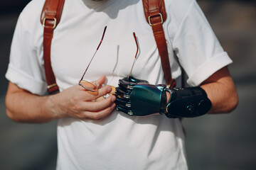Young disabled man portrait put on yellow glasses with artificial prosthetic hand