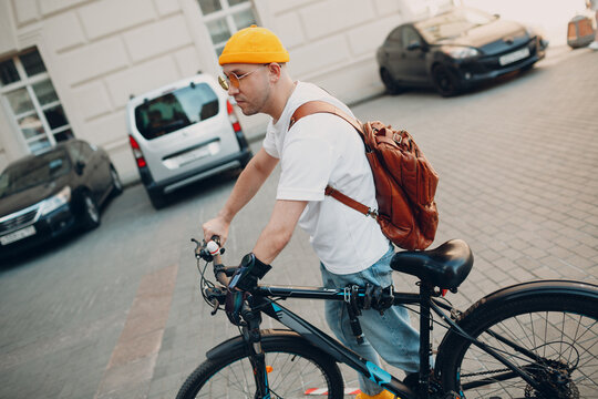 Young disabled man with artificial prosthetic hand in casual clothes riding bicycle